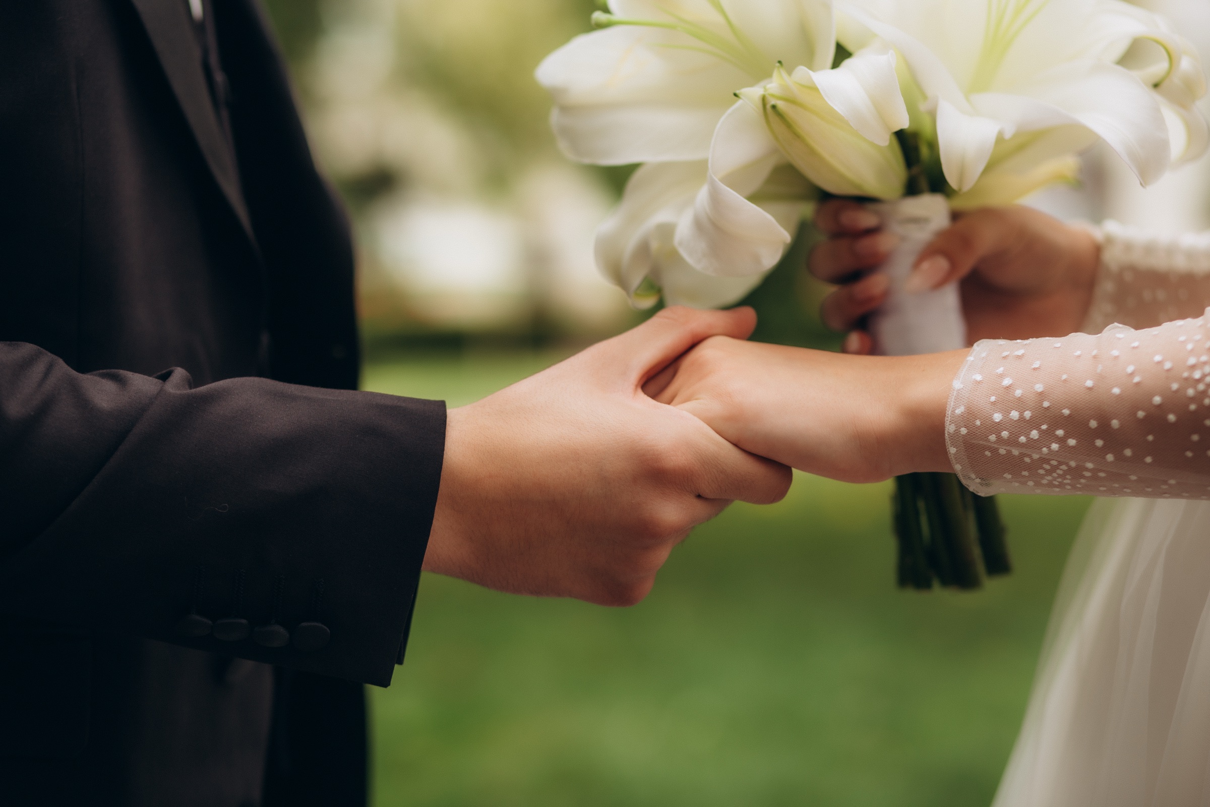 Bride and groom holding hands with white flowers